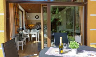 An inviting room with large windows overlooking a terrace. On the table, there are champagne and a plant.