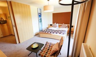 A modern room with a double bed, comfortable pillows, and a small table. The bright decor creates an inviting atmosphere.