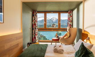 A cozy hotel room with a view of the mountains and a lake. The room is modernly furnished and radiates a relaxed atmosphere.