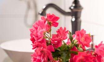 A beautiful bouquet of pink flowers in a green vase. In the background, a sink and a faucet are visible.