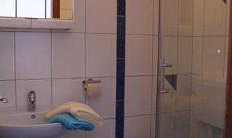 A modern bathroom with white tiles and blue accents. It features a shower, a sink, and a toilet.