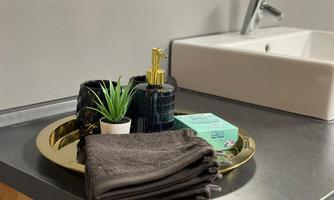 An elegant bathroom setup with towels, soap, and plants on a round tray. The washing area is designed in a modern and stylish way.