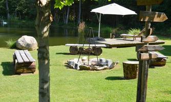 A quiet garden with a pond, a fire pit, and benches. A sun umbrella provides shade on the terrace.