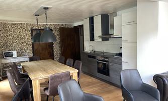 A modern kitchen with a large dining table and elegant chairs. The walls are decorated with an appealing pattern.