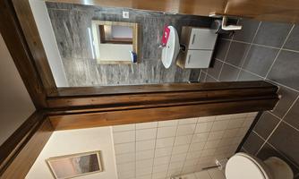 A modern bathroom with a toilet and a sink. The walls are partially tiled, and a mirror is present.