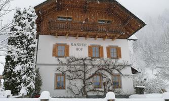 A beautiful house in the snow, surrounded by snow-covered trees. The sky is gray and gentle snow is falling.