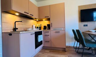 A modern kitchen with bright cabinets and wooden details. It is well-equipped and offers enough space for a dining area.