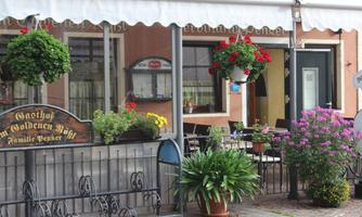 An inviting inn with a colorful display of flowers and a covered outdoor area. The facade is designed in a friendly way and invites you to linger.