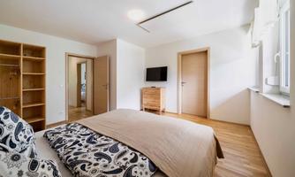 A bright bedroom with a large bed and wooden furniture. There is a television on the wall and two doors that lead to other rooms.