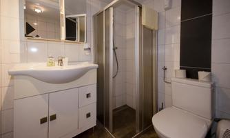 A modern bathroom with a shower, a sink, and a toilet. The walls are decorated with white tiles.