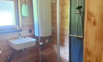 A modern bathroom with wooden paneling. The shower and sink are stylishly and functionally integrated.