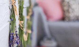 A beautiful area with dried lavender hanging on a wall. In the background, a cozy sofa and decorative cushions are visible.