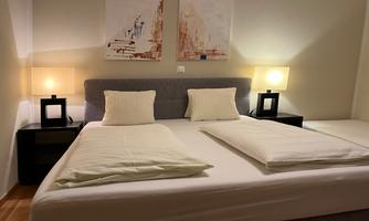 A cozy bedroom with a large bed and modern nightstands. Soft lighting creates a relaxed atmosphere.