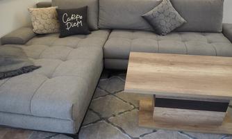 A modern living room with a gray couch and a wooden table. Decorative pillows are on the couch.