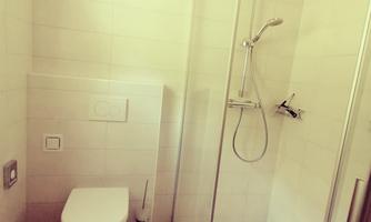A modern bathroom with a shower and toilet. The walls are brightly tiled, and the space feels clean and spacious.