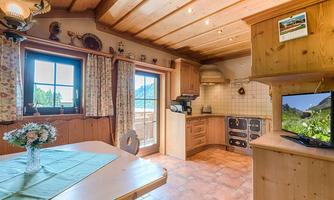 A cozy kitchen with wood interior and a dining table. Large windows let in a lot of light and offer a view outside.