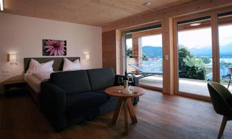 A modern room with a comfortable sofa and a table. Large windows offer a view of the landscape.