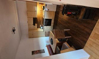 A modern kitchen with a dining table and chairs. The wooden floors and warm colors create an inviting atmosphere.