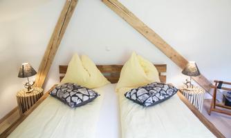 A cozy bedroom with a double bed and yellow pillows. Two nightstands with lamps complete the inviting atmosphere.