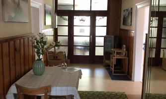 An inviting hallway with a dining area and a large window. The walls are bright, and a carpet adds to the cozy atmosphere.