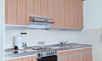 A modern kitchen with red wooden shelves and metallic fixtures. The space feels bright and spacious.