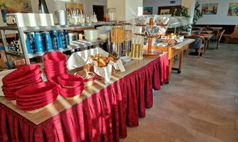 A buffet with various foods and drinks. On the table are red plates, glasses, and sweet pastries arranged.