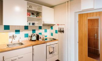 A modern kitchen with white cabinets and a wood countertop. The walls are decorated with blue tiles and kitchen utensils.
