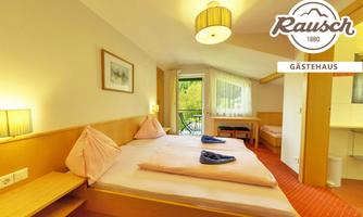 A bright guest room with two beds, a table, and a balcony. The decor is friendly and inviting, with a warm color tone.
