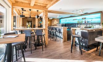 A modern bar with wooden details and elegant seating groups. The color accents and lighting create an inviting atmosphere.