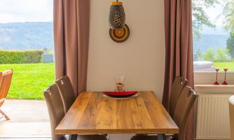 The dining table is positioned between the terrace door and the panoramic window. On warm days, the interior becomes an extension of the lawn outside, making it perfect for family breakfasts in the open air.