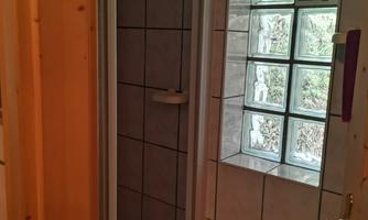 A small shower with tiled walls and a window made of glass blocks. The room feels bright and welcoming.
