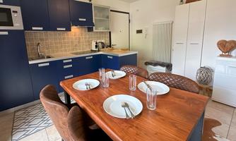A modern kitchen with blue cabinets and a wooden dining table. The table is set for four people.