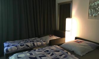 A cozy bedroom with two beds and modern bedding. Curtains and a floor lamp create a relaxed atmosphere.