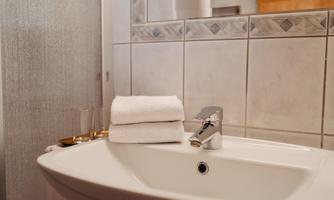 A modern sink in a bathroom with fresh towels. The walls are brightly tiled, creating an inviting atmosphere.
