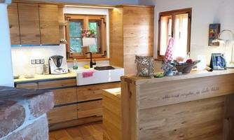 A modern kitchen made of wood with bright cabinets and a large window. The space has rustic details and a welcoming atmosphere.