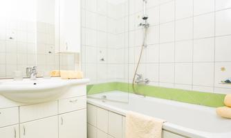 A bright bathroom with a sink and a bathtub. The walls are tiled and designed in fresh colors.