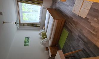 A simple and cozy bedroom with a double bed and pillows. Large windows provide plenty of daylight and a pleasant atmosphere.
