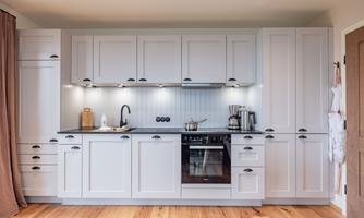 A modern kitchen with bright cabinets and an elegant countertop. The kitchen is well-equipped with a stove, dishes, and cooking utensils.