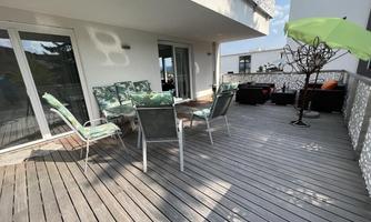 A cozy terrace with garden furniture and a parasol. The wooden platform offers a beautiful view and invites relaxation.