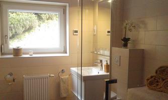 A modern bathroom with a shower and windows that let in natural light. Towels and decorations create an inviting atmosphere.