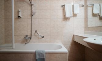 A modern bathroom with a bathtub and a shower. Towels hang on the wall and there is a sink.