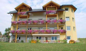 A beautiful building with three floors and blooming balcony boxes. The lawn in front creates a calm, inviting atmosphere.