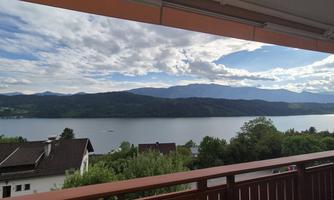 A view of a tranquil lake with mountains in the background. The sky is cloudy and a peaceful landscape can be seen.