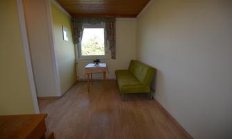 A simple, bright room with a green sofa and a table. Natural light enters the room through the window.