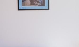 A cozy living room with a pink sofa and a cushion that says "hello." On the wall hangs a frame with a mountain motif.