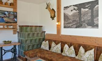 A cozy room with a comfortable couch and decorative cushions. On the wall hang a picture of mountains and a deer antler.
