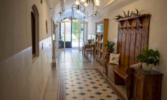 An inviting hallway with wooden coat hooks and a cozy bench. Large windows allow a view outside to the garden.