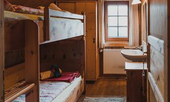 A cozy room with wooden paneling and bunk beds. The window lets in a lot of daylight, and there is a small table.