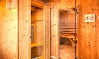 Sauna area with wooden paneling and cozy atmosphere. A changing room leads to the actual sauna.