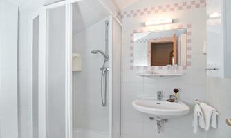 A modern bathroom with a shower and a sink. Walls and tiles are kept in bright white.